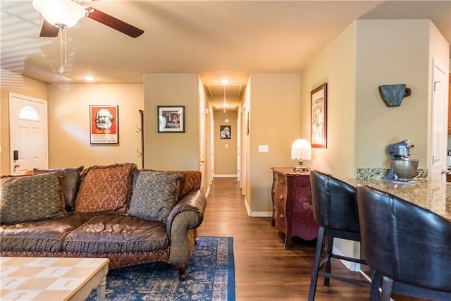 living area featuring attic access, a ceiling fan, baseboards, and wood finished floors