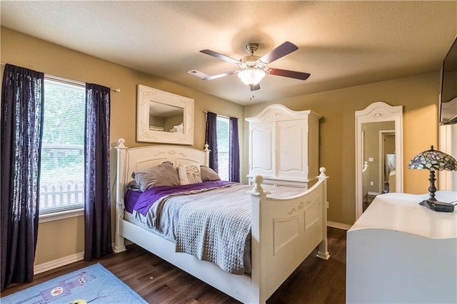 bedroom featuring dark wood-style floors, ceiling fan, multiple windows, and baseboards