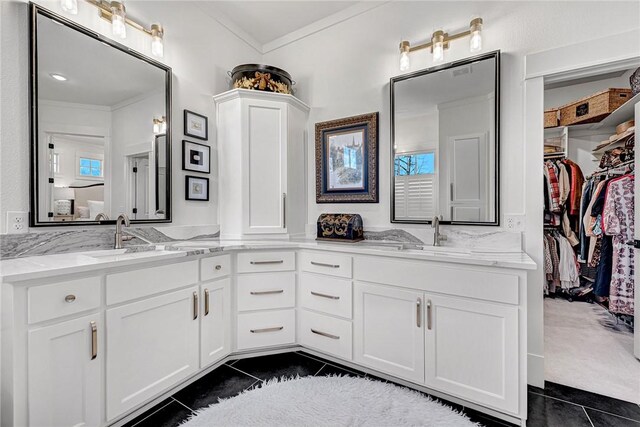 bathroom featuring tile patterned flooring, double vanity, ornamental molding, and a sink