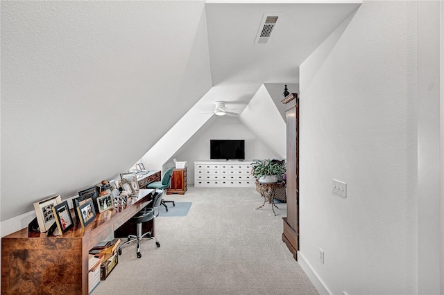 carpeted office featuring lofted ceiling, a ceiling fan, and visible vents