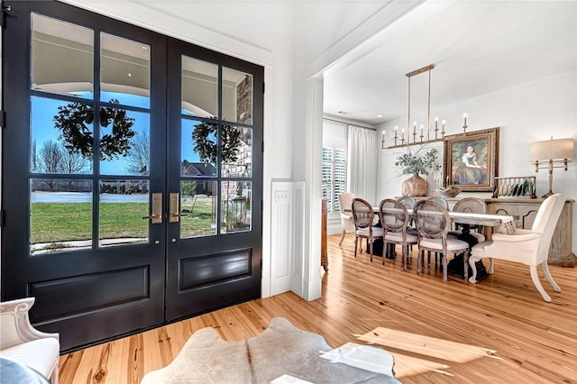 foyer entrance featuring wood finished floors, french doors, and a chandelier