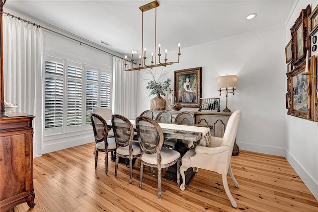 dining room with baseboards, visible vents, ornamental molding, light wood-type flooring, and a chandelier