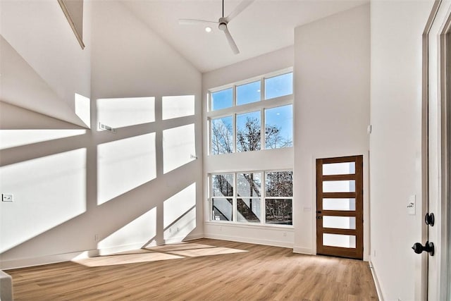 entryway featuring wood finished floors, a ceiling fan, baseboards, and high vaulted ceiling