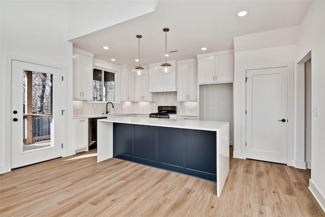 kitchen with backsplash, light countertops, dishwashing machine, white cabinets, and range