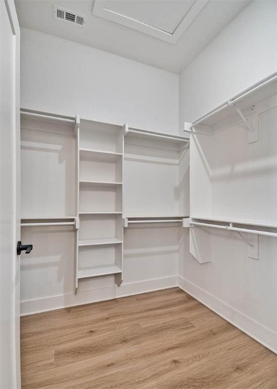 walk in closet featuring visible vents, attic access, and wood finished floors