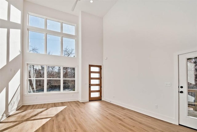 foyer featuring baseboards, wood finished floors, and a towering ceiling