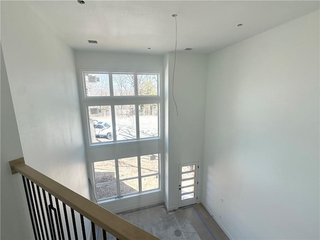 staircase featuring a high ceiling, baseboards, and concrete floors