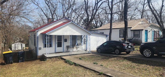 bungalow-style home featuring metal roof, an outbuilding, cooling unit, a porch, and a front yard