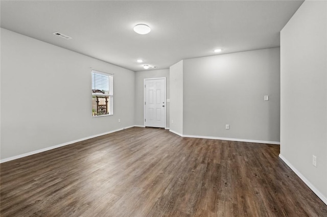 unfurnished room featuring baseboards, visible vents, and dark wood-type flooring