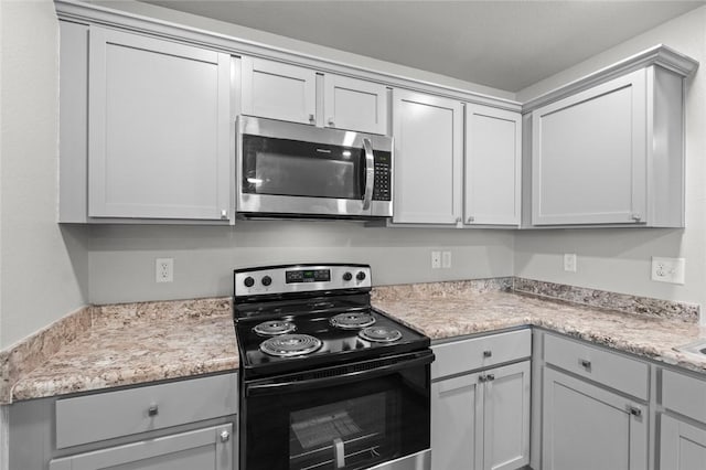 kitchen featuring stainless steel microwave, black electric range oven, and gray cabinetry