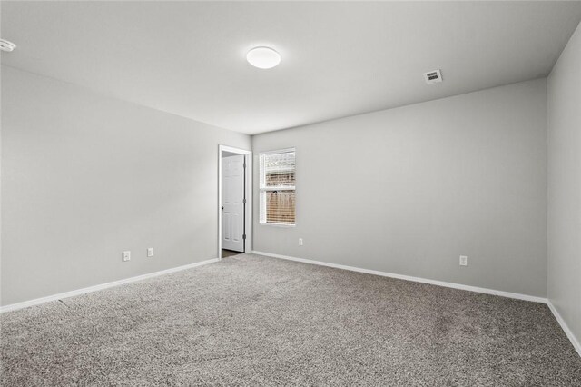 carpeted spare room with visible vents and baseboards