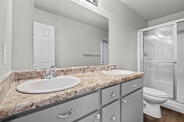 full bath with double vanity, a shower stall, toilet, and a sink