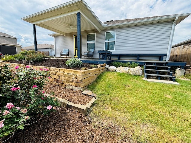 rear view of house featuring a lawn, fence, and ceiling fan