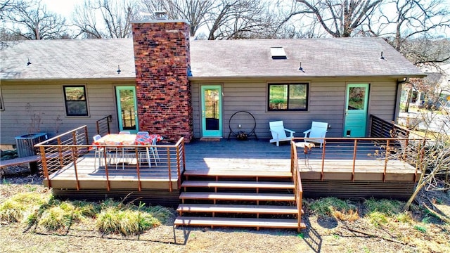 rear view of property with a wooden deck, central AC unit, a chimney, and a shingled roof