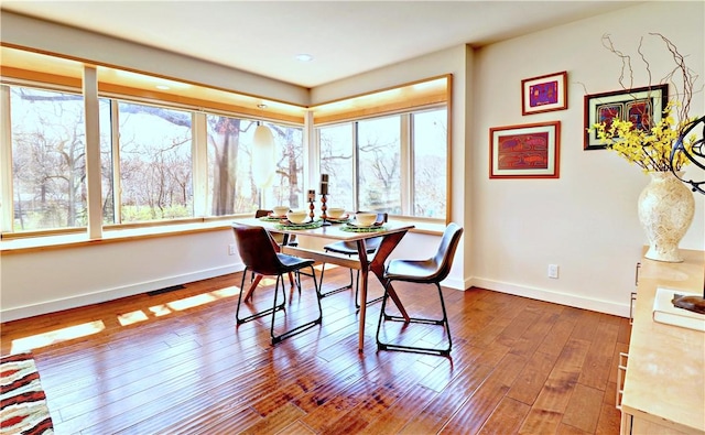 dining area with visible vents, baseboards, and hardwood / wood-style flooring