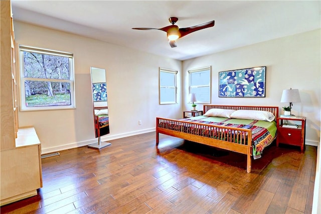 bedroom featuring multiple windows, baseboards, and wood-type flooring