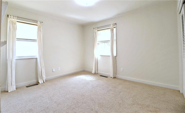 empty room with visible vents, baseboards, carpet, and crown molding