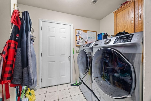 laundry room featuring light tile patterned floors, separate washer and dryer, cabinet space, and visible vents