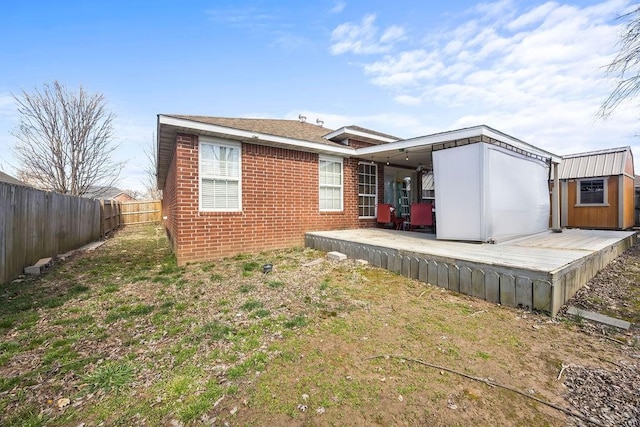 back of house with a fenced backyard, a deck, and brick siding