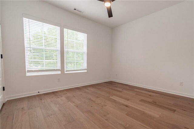 spare room featuring ceiling fan, light wood-style flooring, visible vents, and baseboards