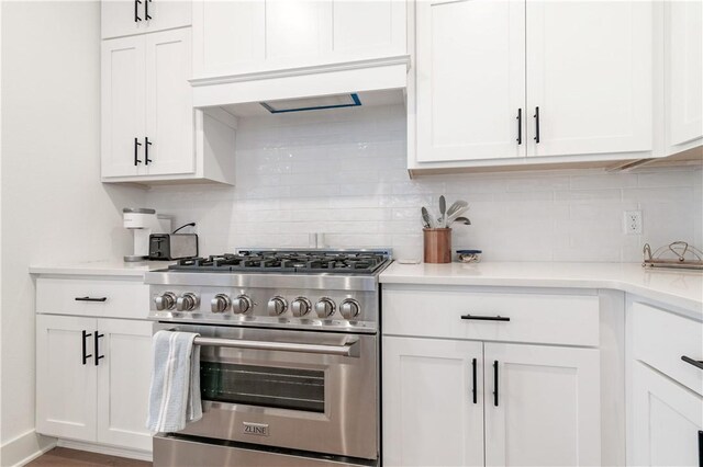 kitchen with tasteful backsplash, white cabinets, and stainless steel range