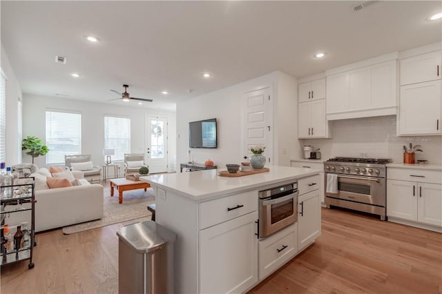 kitchen with stainless steel appliances, light countertops, light wood-style floors, and white cabinetry