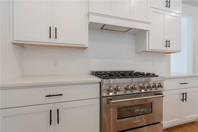 kitchen featuring premium range hood, light countertops, backsplash, and high end stainless steel range