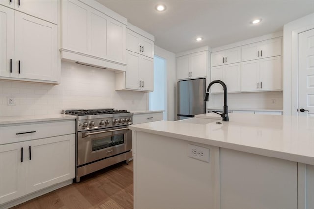 kitchen with dark wood-style flooring, stainless steel appliances, light countertops, white cabinetry, and a sink