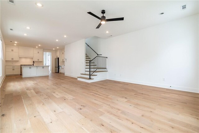 unfurnished living room featuring stairs, light wood finished floors, baseboards, and recessed lighting