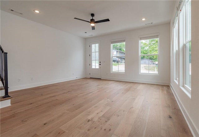 unfurnished living room featuring stairway, plenty of natural light, visible vents, and light wood-style floors