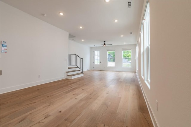 unfurnished living room featuring recessed lighting, visible vents, baseboards, light wood-style floors, and stairway