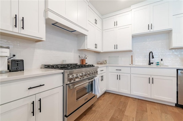 kitchen featuring stainless steel appliances, light countertops, a sink, and light wood-style flooring