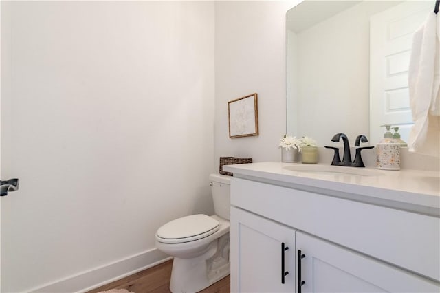 bathroom with wood finished floors, vanity, toilet, and baseboards