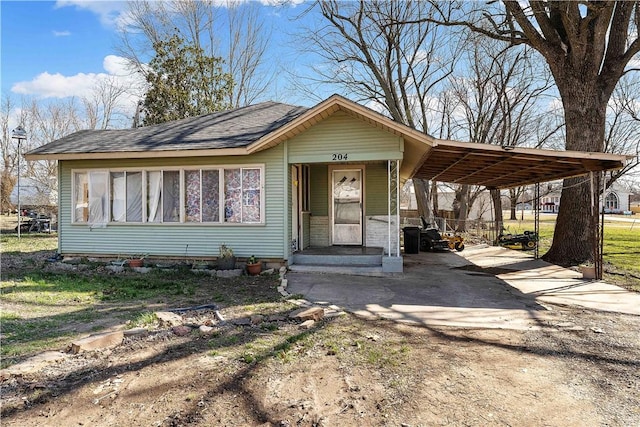 view of front of home featuring concrete driveway, an attached carport, and a shingled roof