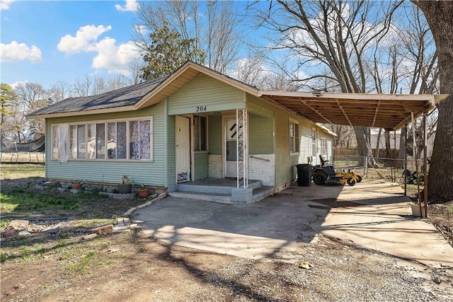 view of front of house featuring driveway, a carport, and roof with shingles