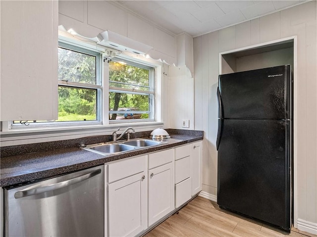 kitchen featuring stainless steel dishwasher, a sink, white cabinets, freestanding refrigerator, and light wood finished floors