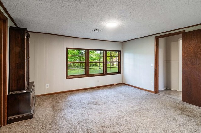 unfurnished bedroom with carpet flooring, crown molding, a textured ceiling, baseboards, and visible vents