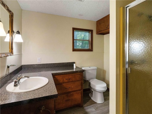full bathroom with toilet, a shower stall, wood finished floors, and vanity