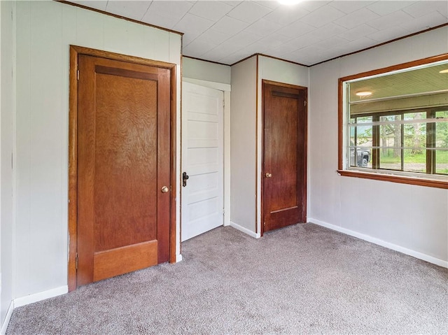 unfurnished bedroom with crown molding, carpet, baseboards, and a closet