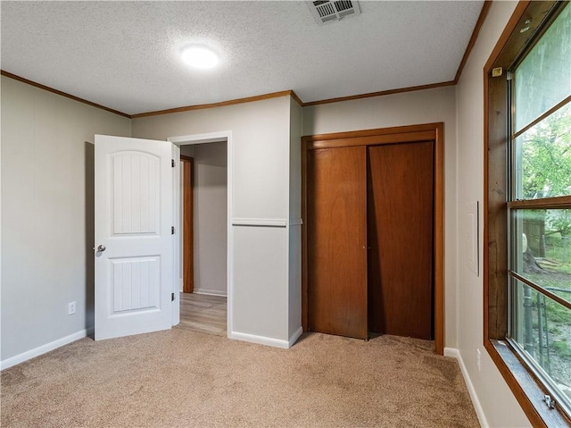 unfurnished bedroom featuring crown molding, a textured ceiling, visible vents, and carpet flooring