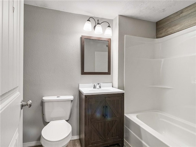 bathroom with vanity, a textured wall, toilet, baseboards, and  shower combination