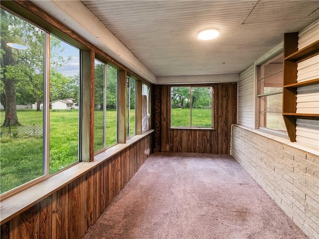 unfurnished sunroom with carpet floors and wood walls
