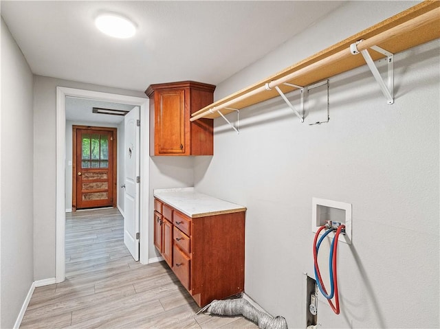 laundry room featuring light wood-type flooring, hookup for a washing machine, cabinet space, and baseboards