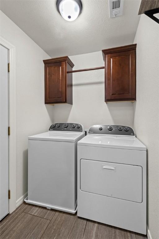 laundry room with independent washer and dryer, cabinet space, wood finished floors, and baseboards
