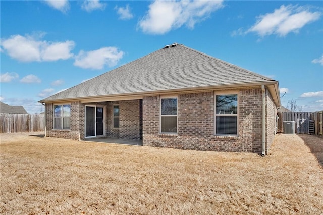 rear view of property featuring roof with shingles, brick siding, a patio area, and central AC