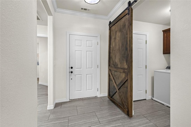 entrance foyer featuring a barn door, washer / dryer, crown molding, and baseboards
