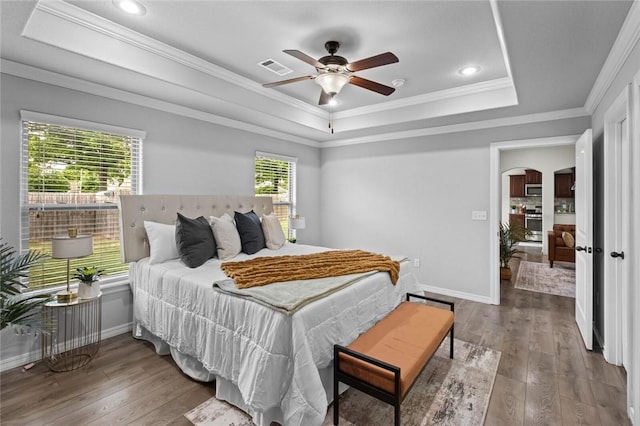 bedroom with a raised ceiling, hardwood / wood-style floors, baseboards, ornamental molding, and recessed lighting