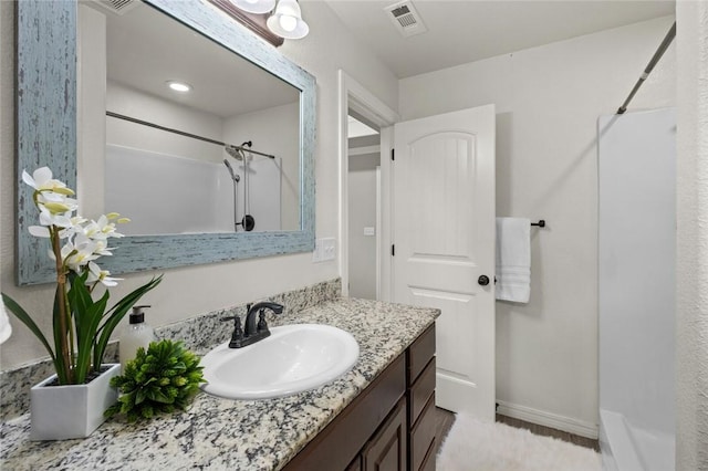 bathroom with a shower, vanity, and baseboards