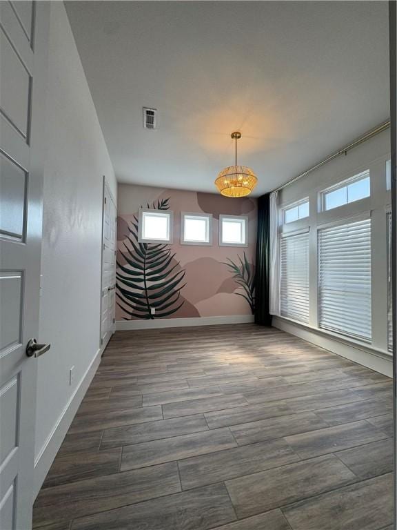 spare room featuring dark wood-type flooring, visible vents, and baseboards