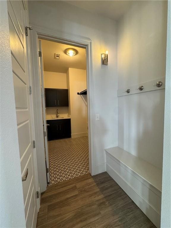 mudroom with dark wood-style floors, a sink, and baseboards